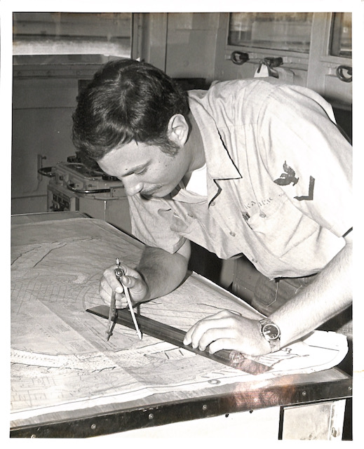 Me in Navy work uniform at a chart table navigating.