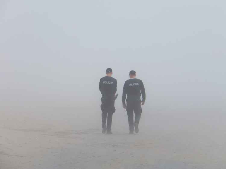 Two foreign police officers walking away together in the fog.