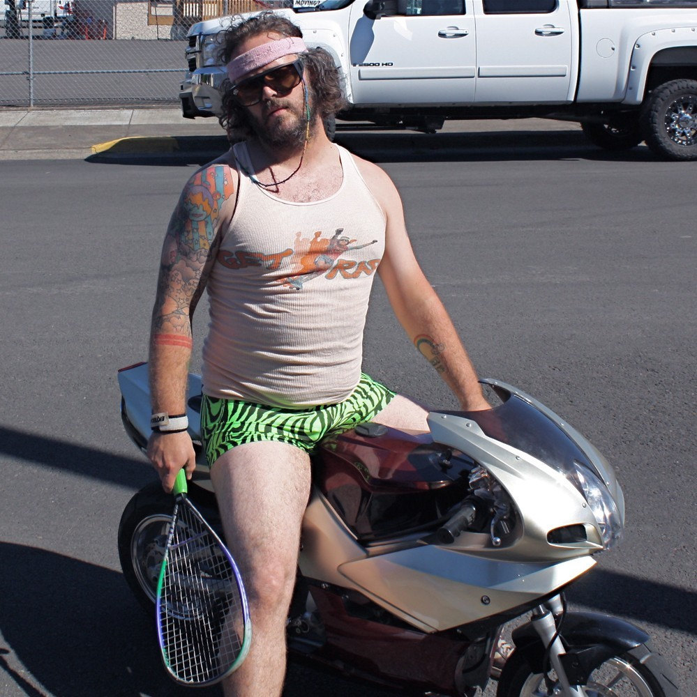 Man on small motorcycle wearing a wife beater t-shirt